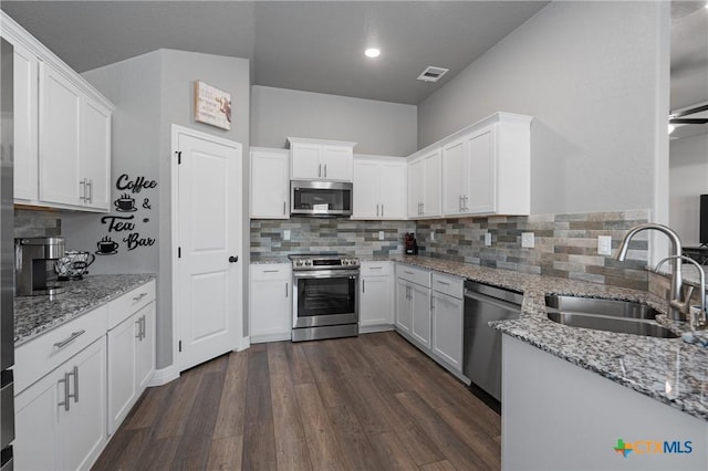 2446 Moreno Spur, Temple, TX 76501 - kitchen with tasteful backsplash, white cabinetry, stainless steel appliances, a sink, and dark wood-style floors