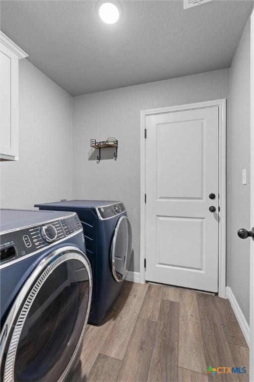 2446 Moreno Spur, Temple, TX 76501 - clothes washing area featuring cabinet space, washing machine and clothes dryer, wood finished floors, and baseboards