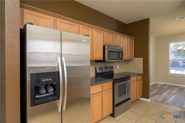 2109 Vernice Dr, Copperas Cove, TX 76522 - kitchen with light tile patterned floors, visible vents, decorative backsplash, dark countertops, and appliances with stainless steel finishes
