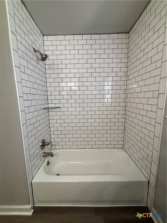 bathroom with hardwood / wood-style floors and tiled shower / bath combo