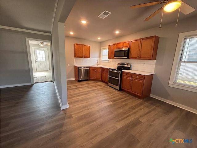 kitchen featuring sink, backsplash, ceiling fan, stainless steel appliances, and dark wood-type flooring