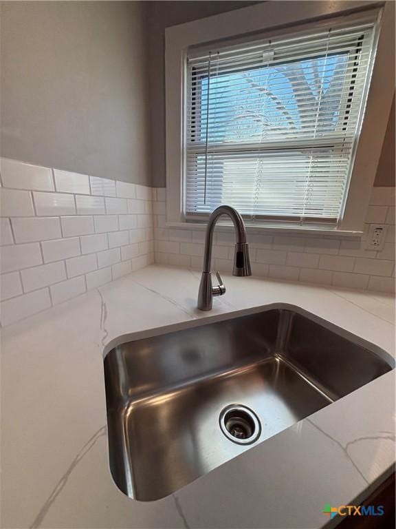 room details with light stone countertops, sink, and backsplash