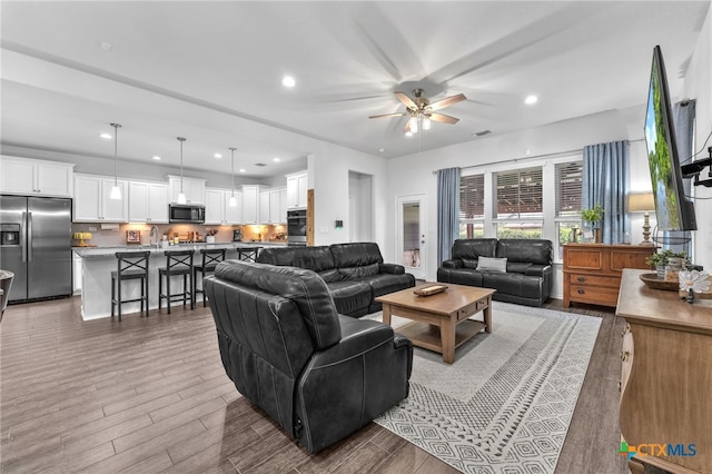 living room with hardwood / wood-style flooring, ceiling fan, and sink