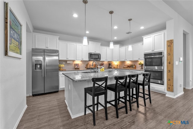 kitchen featuring hanging light fixtures, white cabinets, and stainless steel appliances