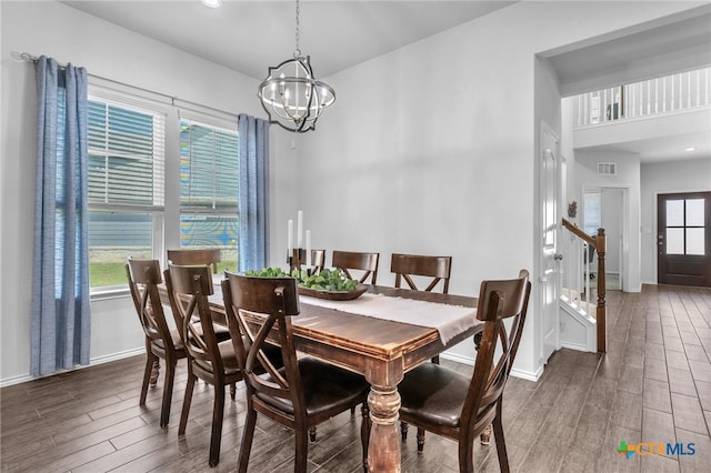 dining space with dark wood-type flooring and an inviting chandelier