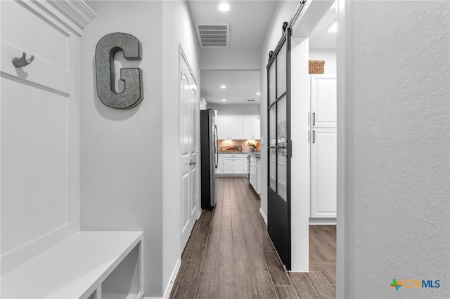 hallway with a barn door and dark wood-type flooring