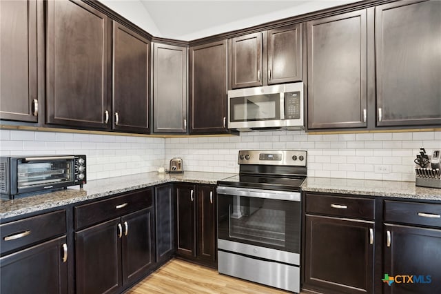 kitchen with appliances with stainless steel finishes, decorative backsplash, dark brown cabinetry, and light hardwood / wood-style flooring