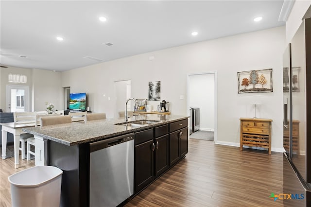 kitchen featuring light stone counters, dark hardwood / wood-style floors, sink, an island with sink, and stainless steel dishwasher