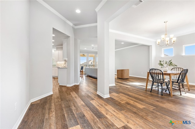 dining room with a chandelier, ornamental molding, and dark wood-type flooring