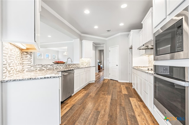 kitchen with white cabinets, light stone counters, dark wood-type flooring, and appliances with stainless steel finishes