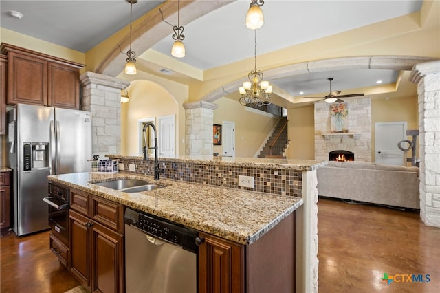 kitchen featuring pendant lighting, a fireplace, sink, a tray ceiling, and stainless steel appliances