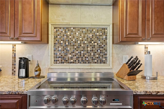 kitchen featuring stainless steel range with electric stovetop, light stone countertops, and backsplash