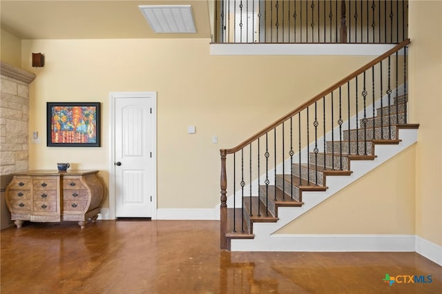 stairway with concrete floors and a high ceiling