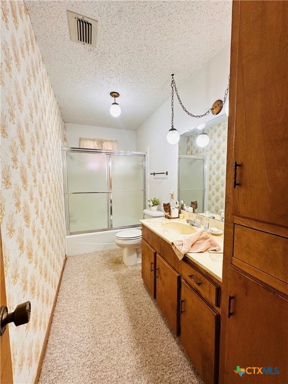 full bathroom with vanity, a textured ceiling, combined bath / shower with glass door, and toilet