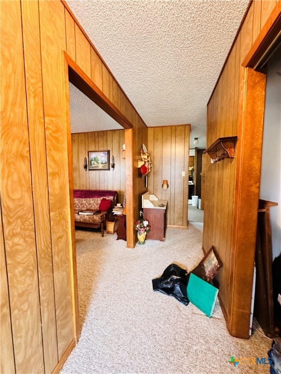 bedroom featuring wood walls, a textured ceiling, and carpet flooring