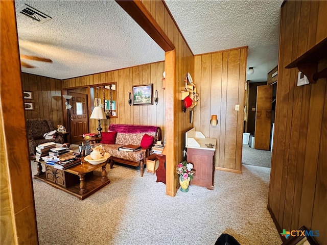 living room with wooden walls, a textured ceiling, and carpet flooring