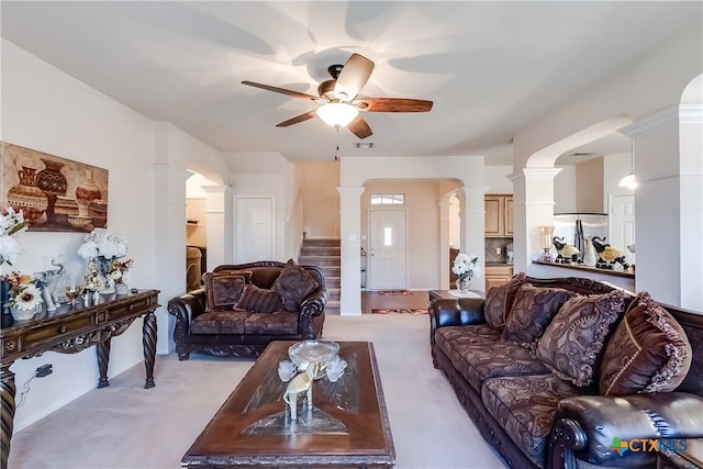 carpeted living room with ceiling fan and ornate columns