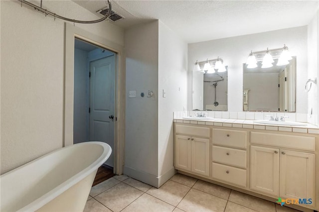 bathroom with vanity, a tub to relax in, tile patterned floors, and a textured ceiling