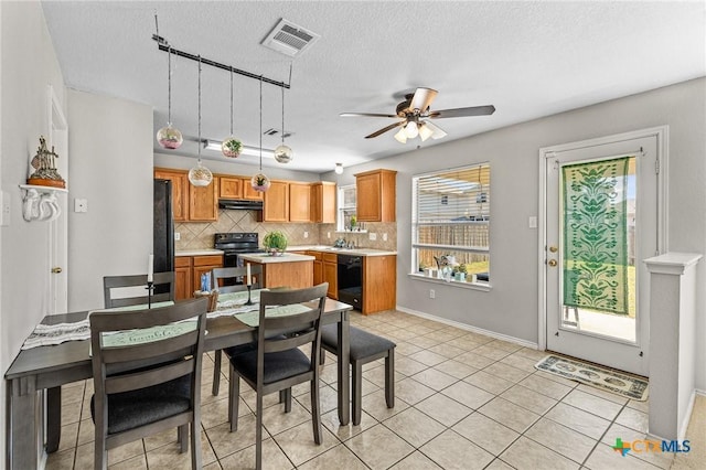 dining room with a textured ceiling, visible vents, and a ceiling fan