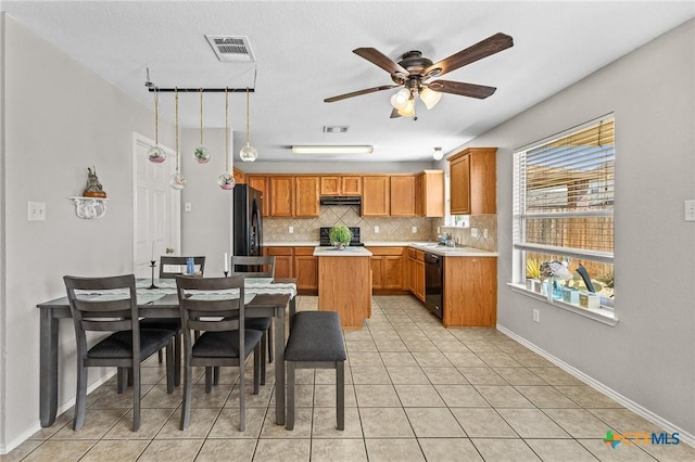 kitchen featuring tasteful backsplash, visible vents, under cabinet range hood, light countertops, and black appliances