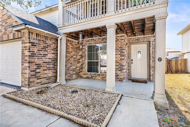 property entrance with a garage, brick siding, fence, and roof with shingles