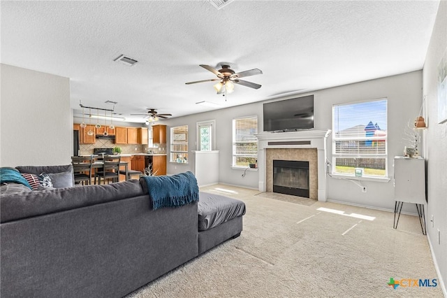 living room with light carpet, plenty of natural light, a tile fireplace, and visible vents