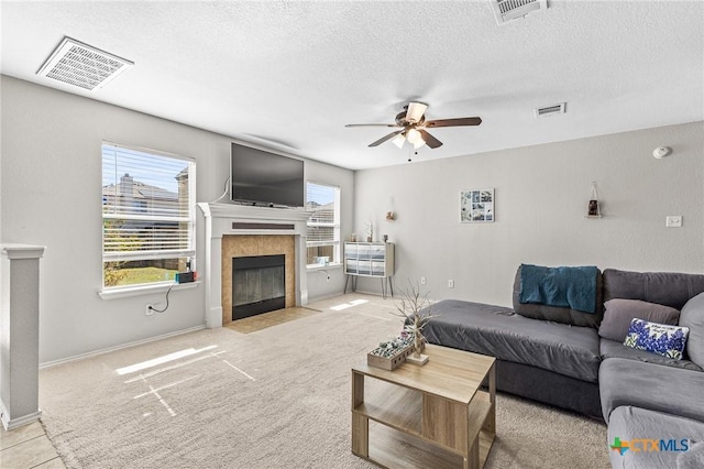 living room with a healthy amount of sunlight, visible vents, and a tiled fireplace