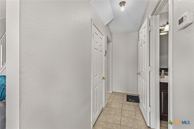 hallway featuring light tile patterned floors and a textured wall