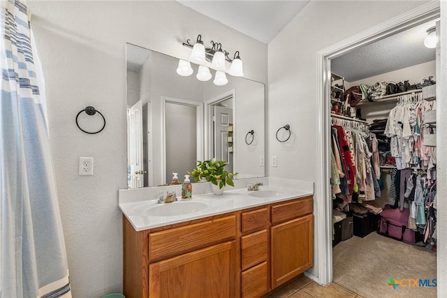 full bath featuring double vanity, a spacious closet, a sink, and tile patterned floors