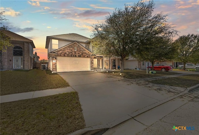 traditional-style home featuring brick siding, a yard, central AC, a garage, and driveway