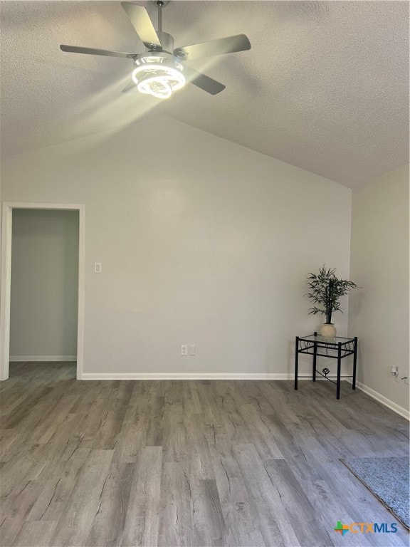 spare room with light hardwood / wood-style floors, ceiling fan, a textured ceiling, and vaulted ceiling