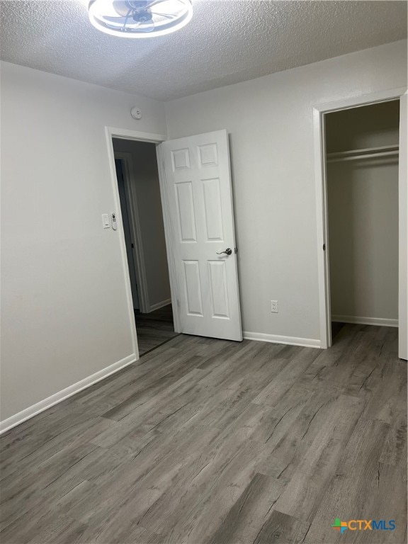 unfurnished bedroom featuring a closet, hardwood / wood-style floors, and a textured ceiling