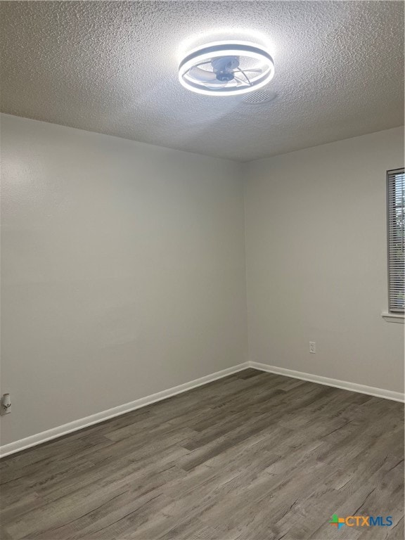 unfurnished room featuring dark wood-type flooring and a textured ceiling