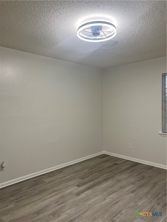 spare room featuring a textured ceiling and dark hardwood / wood-style floors