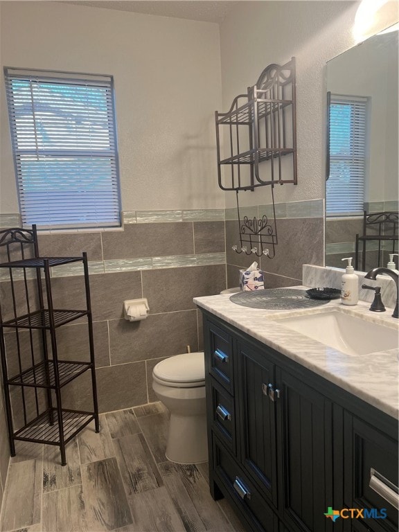 bathroom featuring tile walls, hardwood / wood-style floors, vanity, and toilet