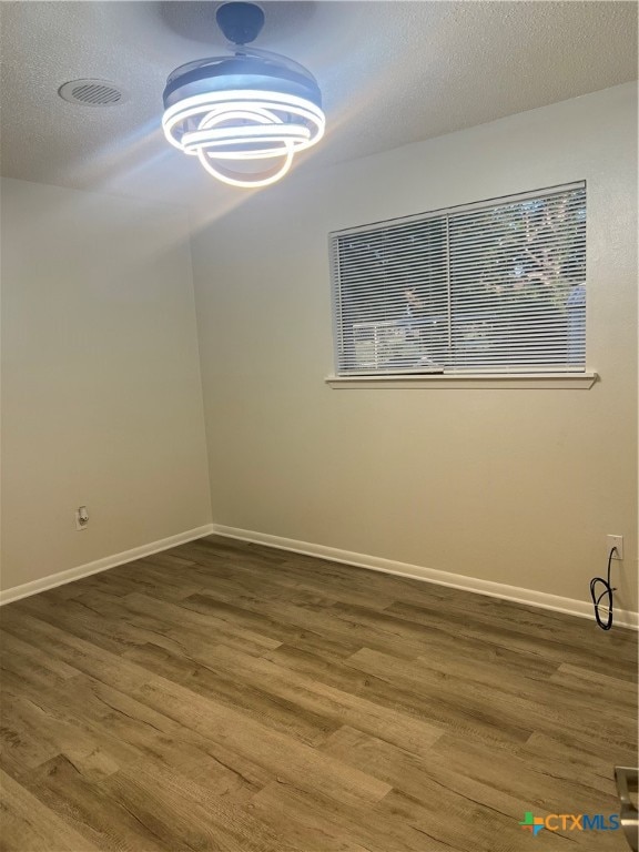 spare room with dark hardwood / wood-style flooring and a textured ceiling