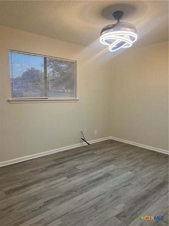 unfurnished room featuring dark wood-type flooring and a textured ceiling