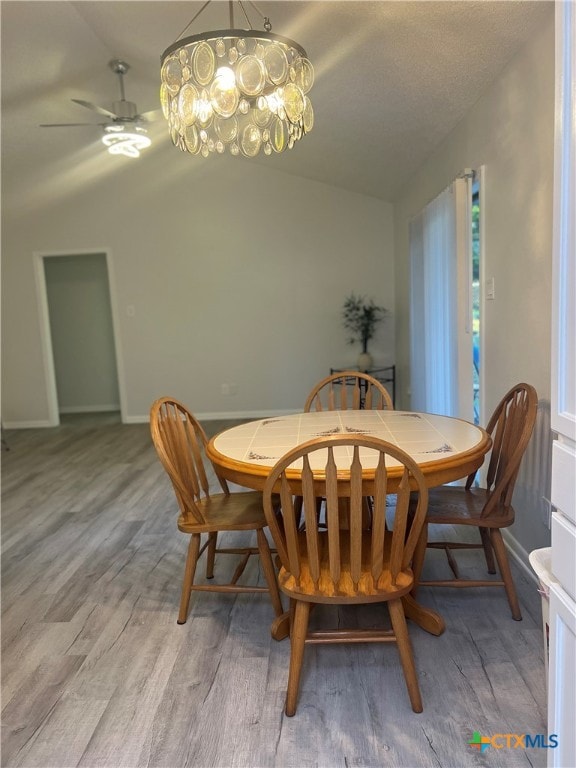 dining area with ceiling fan, wood-type flooring, and lofted ceiling