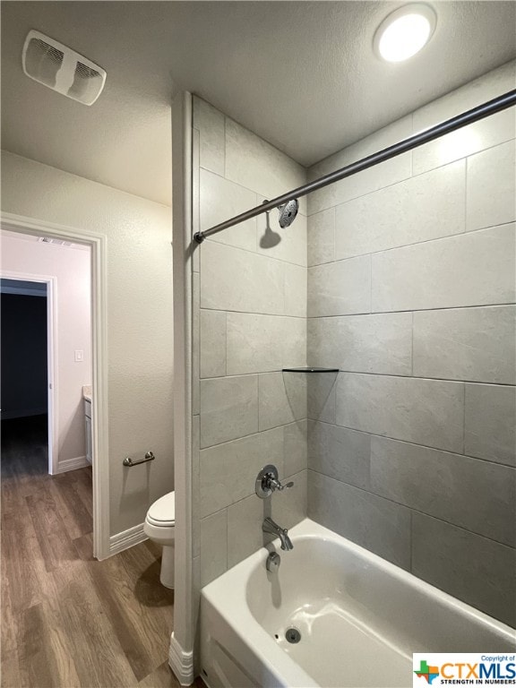 full bathroom with hardwood / wood-style flooring, a textured ceiling, vanity, toilet, and tiled shower / bath combo