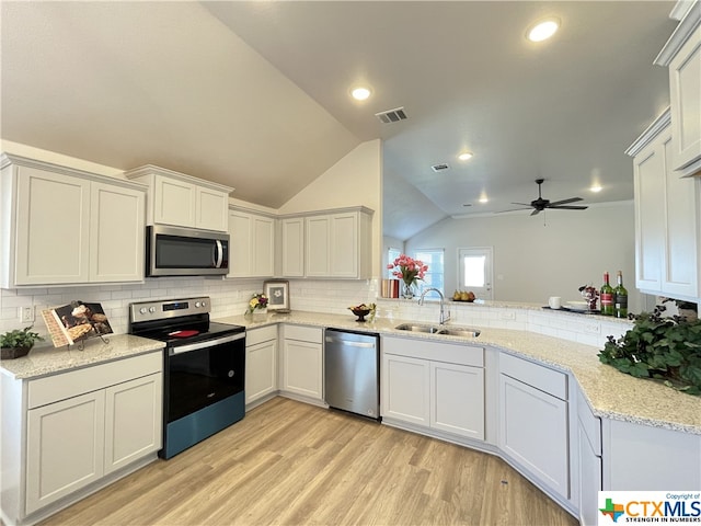 kitchen featuring sink, kitchen peninsula, appliances with stainless steel finishes, light wood-type flooring, and vaulted ceiling