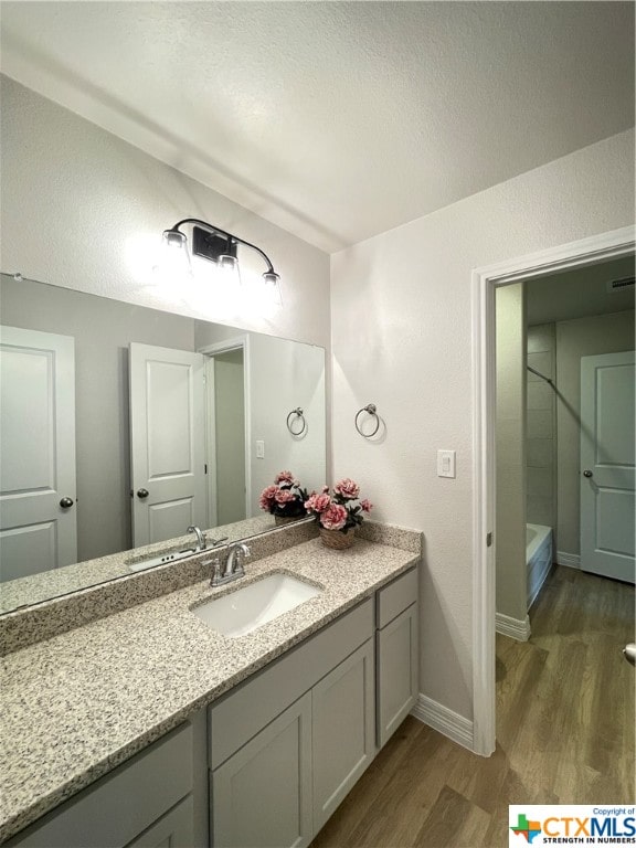 bathroom with hardwood / wood-style flooring, vanity, a textured ceiling, and walk in shower