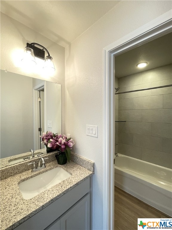 bathroom with vanity, tiled shower / bath, and hardwood / wood-style flooring