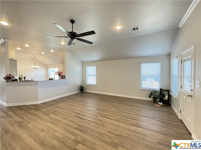 unfurnished living room featuring ceiling fan with notable chandelier, wood-type flooring, a textured ceiling, and vaulted ceiling