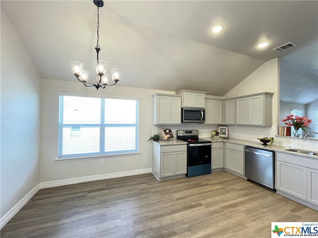 kitchen featuring light hardwood / wood-style floors, sink, appliances with stainless steel finishes, lofted ceiling, and pendant lighting