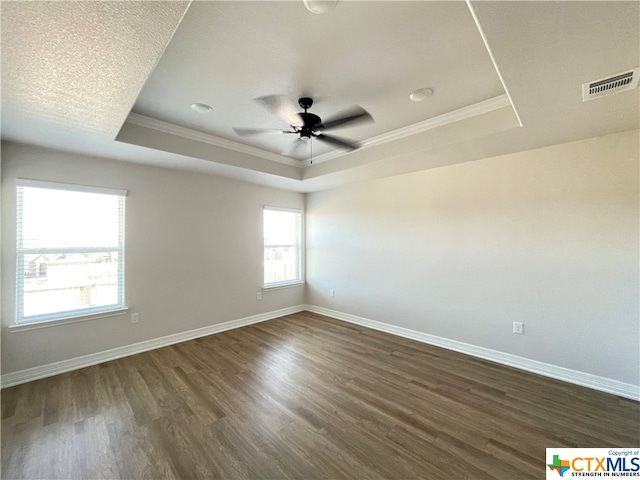 unfurnished room featuring dark hardwood / wood-style flooring, a wealth of natural light, ceiling fan, and a raised ceiling