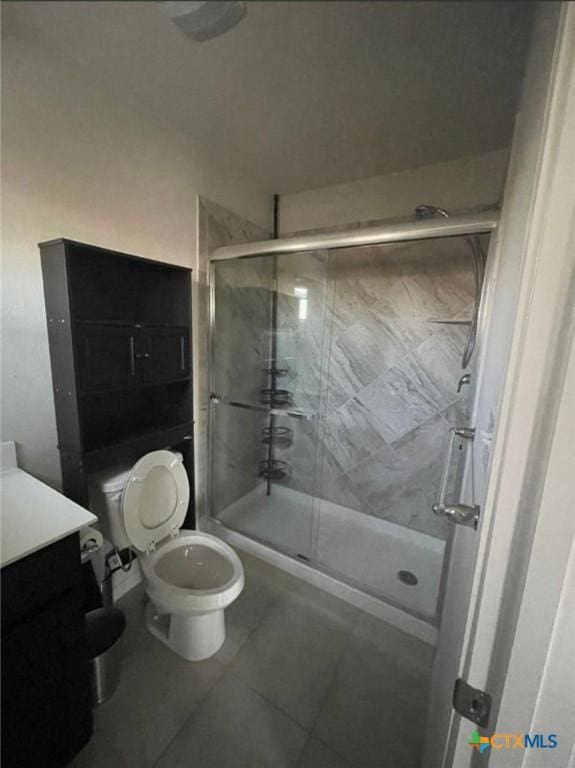 bathroom featuring tile patterned floors, toilet, walk in shower, and vanity