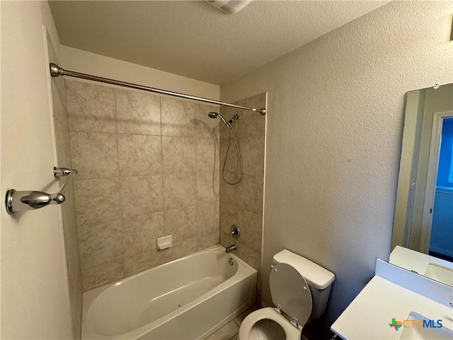 bathroom with a textured ceiling, toilet, and tiled shower / bath