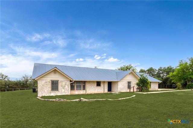 ranch-style house with stone siding, a front yard, and metal roof