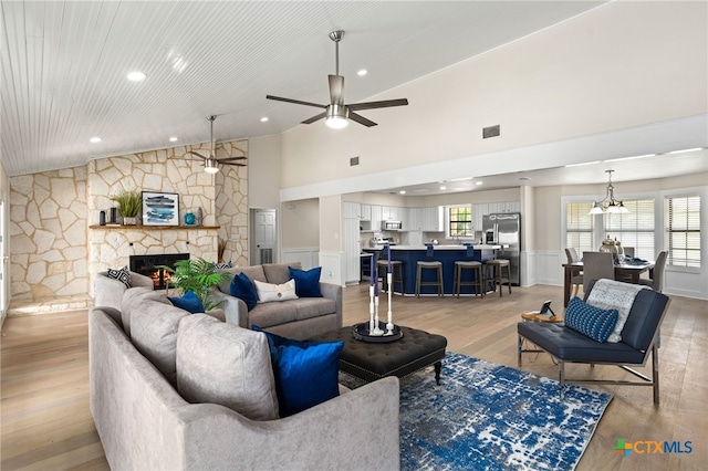 living room with light wood-type flooring, a wealth of natural light, ceiling fan, and visible vents