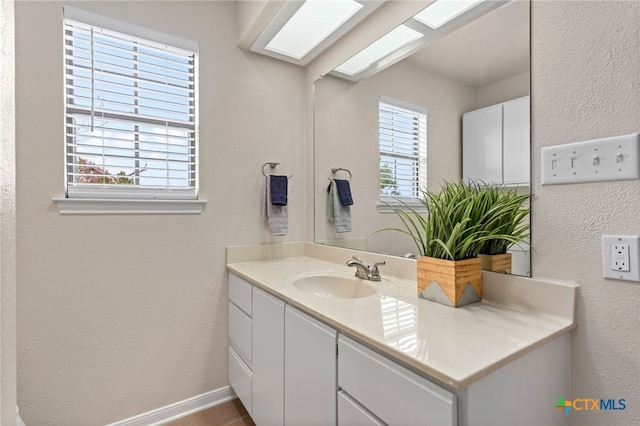 bathroom with vanity, a textured wall, and baseboards